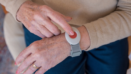 Seniorin trägt Armband mit Funksender: Ein Hausnotrufsystem kann älteren Frauen bei einem möglichen Herzinfarkt das Leben retten.