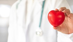 Ein Arzt erklärt, was  LDL-Cholesterin ist, und hält dafür ein Herz in der Hand.