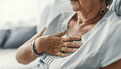 Frau mit Herzinfarkt, verursacht durch zu hohe Cholesterinwerte, hält sich die Hand an die Brust.